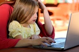 Parent and child sitting together for online school sessions.
